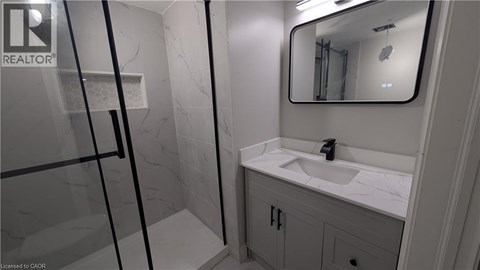 A bathroom with a sink, mirror, and shower.