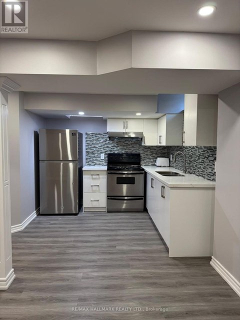 A modern kitchen with a stainless steel refrigerator and a tiled backsplash.