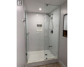 A shower area with a glass door and a tiled floor.