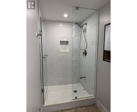A shower area with a glass door and a tiled floor.