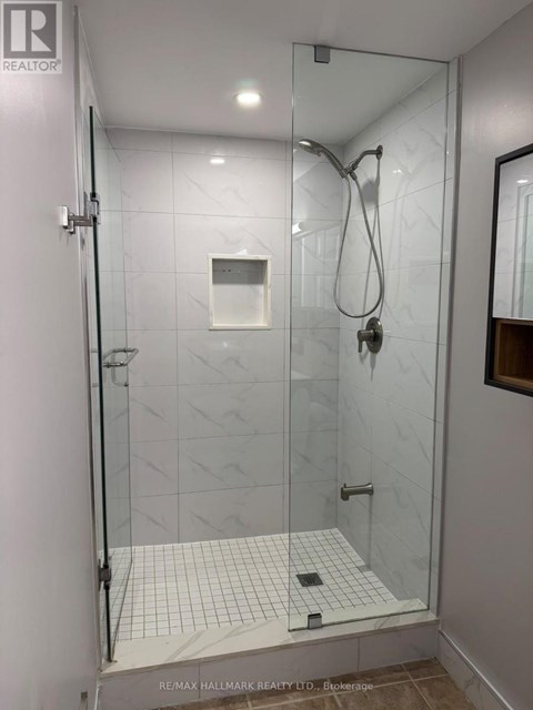 A shower area with a glass door and a tiled floor.
