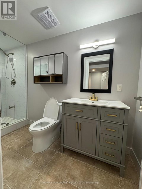 A bathroom with a toilet, sink, and mirror.