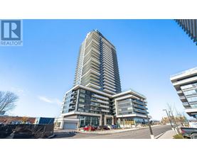 A tall residential building with a glass facade stands in the foreground of a sunny day.