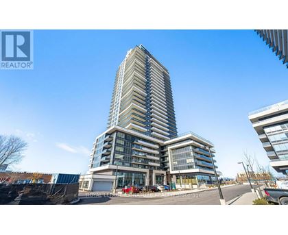 A tall residential building with a glass facade stands in the foreground of a sunny day.
