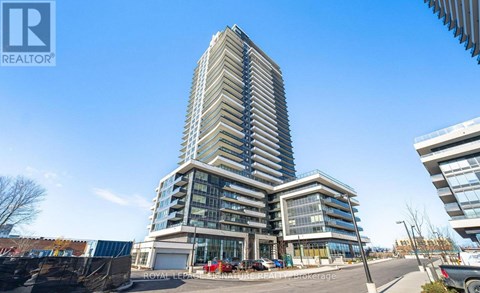 A tall residential building with a glass facade stands in the foreground of a sunny day.