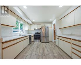 A kitchen with white cabinets and a wooden floor.