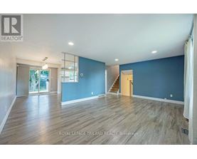 A spacious room with wooden flooring and a staircase leading to another room.