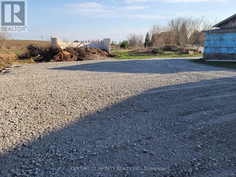 A gravel area with a blue building and a REALTOR sign in the corner.