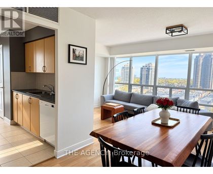 A modern kitchen with a dining table set with a vase of flowers.