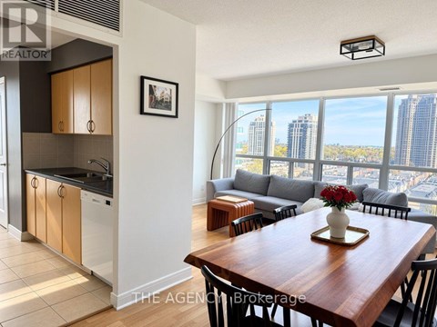 A modern kitchen with a dining table set with a vase of flowers.