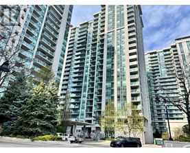 A tall building with many windows is surrounded by trees and has a car parked in front.