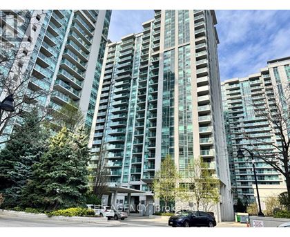 A tall building with many windows is surrounded by trees and has a car parked in front.