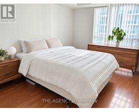 A bedroom with a large bed and a wooden dresser.