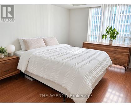 A bedroom with a large bed and a wooden dresser.