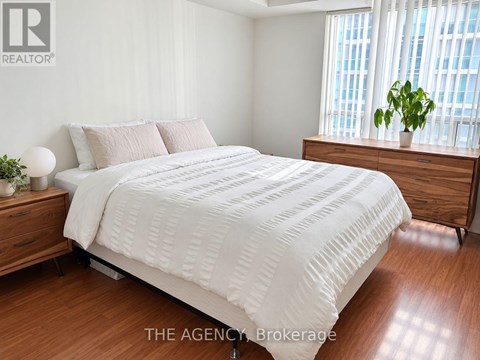 A bedroom with a large bed and a wooden dresser.