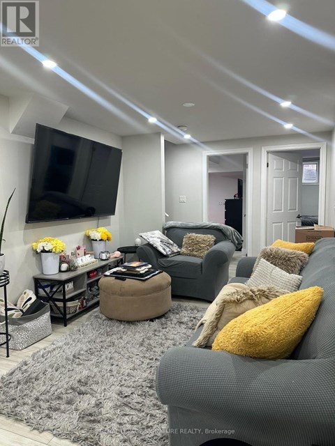 A living room with a grey couch and a flat screen TV mounted on the wall.