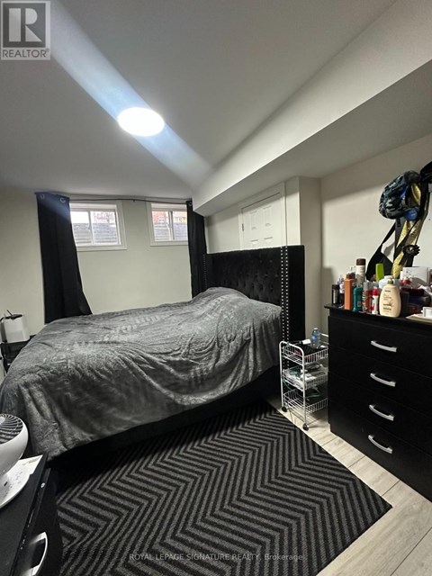 A bedroom with a bed, dresser, and a striped rug.
