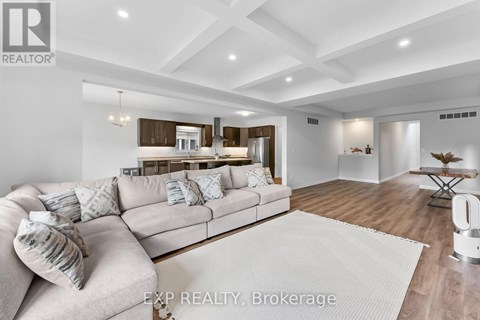 A modern living room with a large couch and a kitchen in the background.