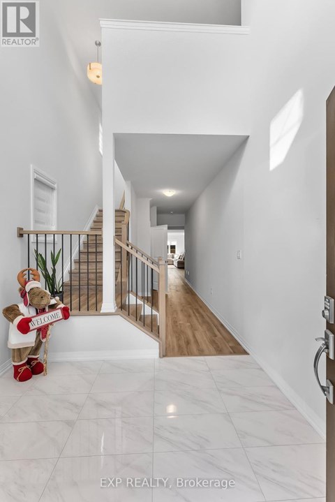 A hallway with a white marble floor and a wooden staircase.