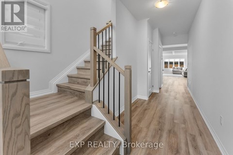 A hallway with wooden floors and a staircase with a wooden handrail.