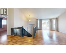 A spacious room with wooden floors and a staircase.