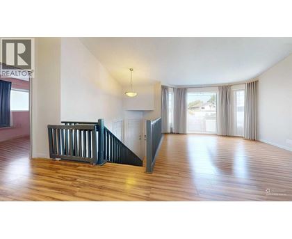 A spacious room with wooden floors and a staircase.