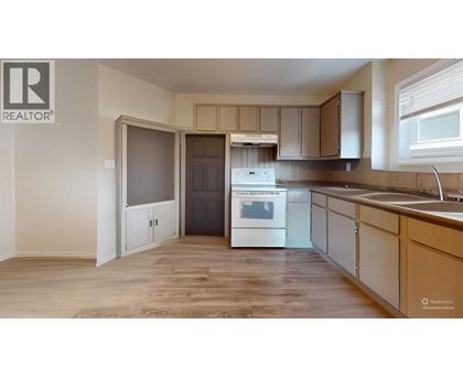 A kitchen with a white stove top oven and wooden flooring.
