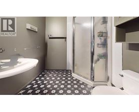 A bathroom with a black and white floor and a glass shower door.