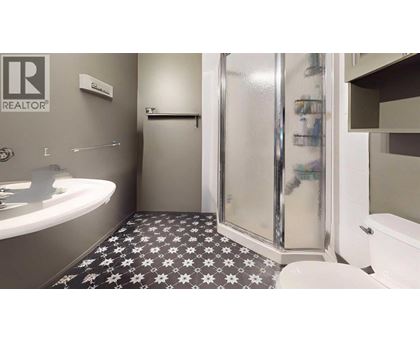 A bathroom with a black and white floor and a glass shower door.