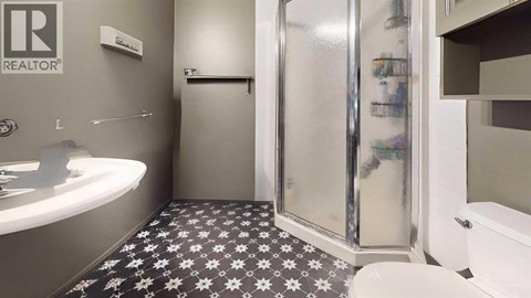 A bathroom with a black and white floor and a glass shower door.