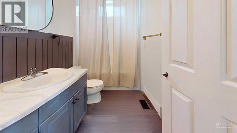 A bathroom with a sink, toilet and shower curtain.