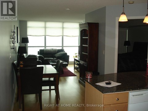 A living room with a couch, a dining table and a kitchen area.