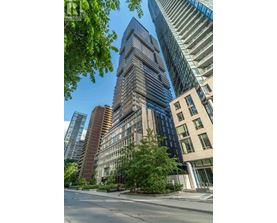 A tall building with many windows stands in the middle of a city street.