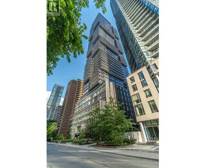 A tall building with many windows stands in the middle of a city street.