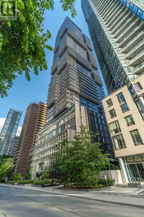 A tall building with many windows stands in the middle of a city street.