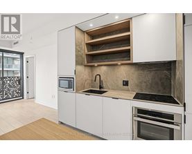 A modern kitchen with white cabinets and a wooden shelf above the sink.