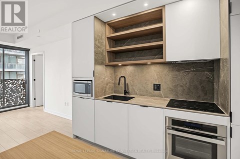 A modern kitchen with white cabinets and a wooden shelf above the sink.