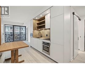 A modern kitchen with white cabinets and a wooden table.