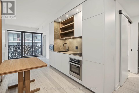 A modern kitchen with white cabinets and a wooden table.