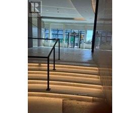 A staircase with a black railing and lighting on the steps.