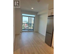 A spacious room with wooden flooring and a large window overlooking a balcony.