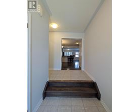A hallway with a wooden staircase leading to a dining area.