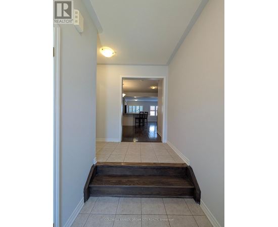 A hallway with a wooden staircase leading to a dining area.