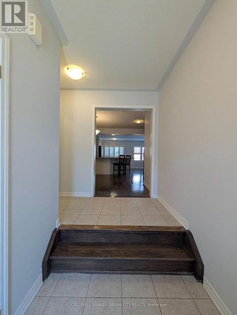 A hallway with a wooden staircase leading to a dining area.