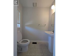 A white toilet sits in a small bathroom with a sink and mirror.