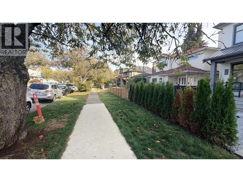 A residential street with houses on both sides and a sidewalk in the foreground.