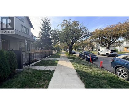 A residential street with cars parked on the side and a realtor's office in the background.