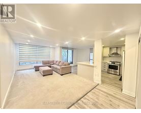 A spacious living room with a couch and a kitchen area in the background.
