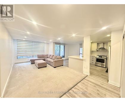 A spacious living room with a couch and a kitchen area in the background.