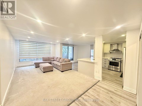 A spacious living room with a couch and a kitchen area in the background.